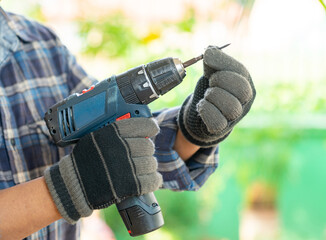 Close up cordless screwdriver and screw bolts in the hands of a carpenter