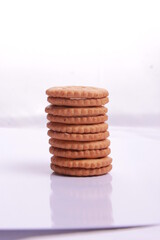 Selective focus of pile of peanut cookies and a piece of biscuit, white background front view