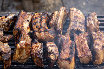 Tasty and delicious barbeque pork ribs grilled, fried outside, outdoor, on wood charcoal grill. national barbeque day. street food. BBQ cooking and man's hands holdings forks.