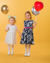 Children with balloons on a yellow background. Birthday, holiday for small