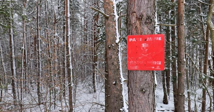 Red mine sign marks the edge of a known minefield  in the forest in Bosnia and Herzegovina. Danger mines. Snow and winter. Aftermath of war. Scars of armed conflict.
