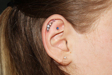 Girl's ear with three ear cartilage piercings and one lobe piercing with beautiful piercing jewelry...