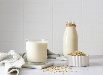 Glass glass cup with barley milk on a marble stand. A clear bottle of milk and barley grains in a...