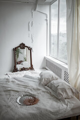 Interior of loft studio apartment in light colors, leather armchair, bed and mirror, retro dishes
