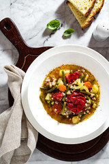 summer italian minestrone soup with tomatoes and homemade bread on a marble table