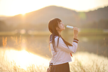 Asian High School Girls student eating ice cream in countryside with sunrise