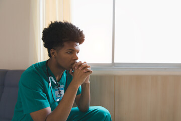 Shot of a young doctor looking distressed. Tired exhausted male african scrub nurse wears green...