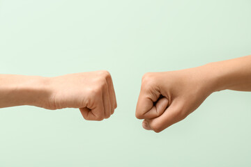 Hands of women with clenched fists on color background