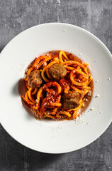 homemade spaghetti with tomato sauce, parmesan and meatballs on a dark background
