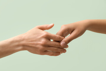 Women holding hands together on color background