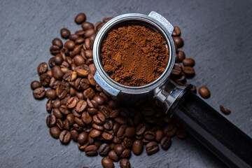 Ground coffee and coffee beans on a black background. Preparing coffee in a coffee machine.