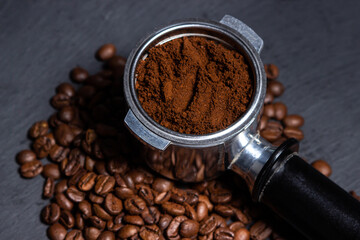 Ground coffee and coffee beans on a black background. Preparing coffee in a coffee machine.