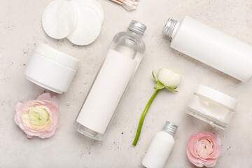 Set of cosmetic products, cotton pads and ranunculus flowers on light background