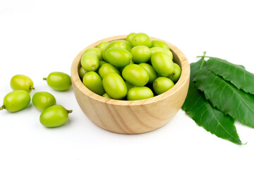 Fresh Neem fruit on wooden bowl with green leaf isolated on white background. Neem fruit is an excellent moisturizing and contains various compounds that have insecticidal and medicinal properties.