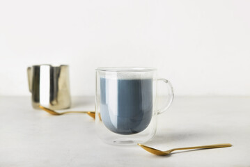 Glass cup of Charcoal Latte and spoon on light table