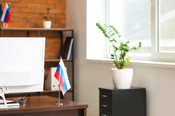 Russian flag and computer on dark wooden table in office