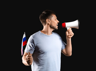 Man with flag of Russia and megaphone on dark background