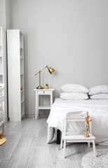 Stepladder stool with mannequin doll and nightstand with lamp and houseplant near bed