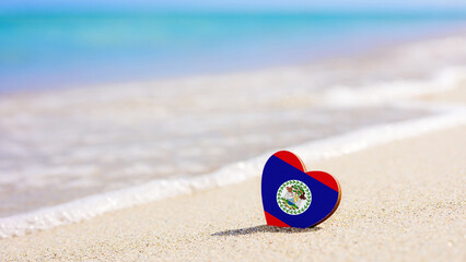 Flag of Belize in the shape of a heart on a sandy beach. The concept of the best holiday in Belize