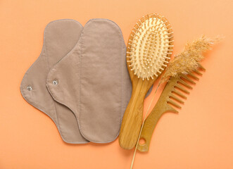 Reusable menstrual pads and hair brushes on orange background