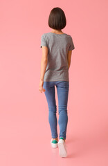 Fototapeta premium Beautiful young woman in stylish t-shirt on color background, back view