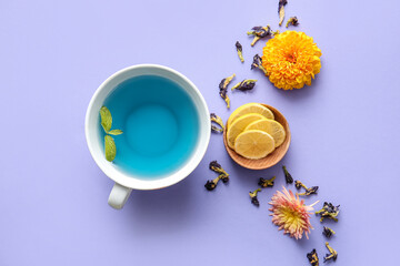 Fototapeta na wymiar Composition with cup of blue tea, lemon and dried butterfly pea flowers on color background