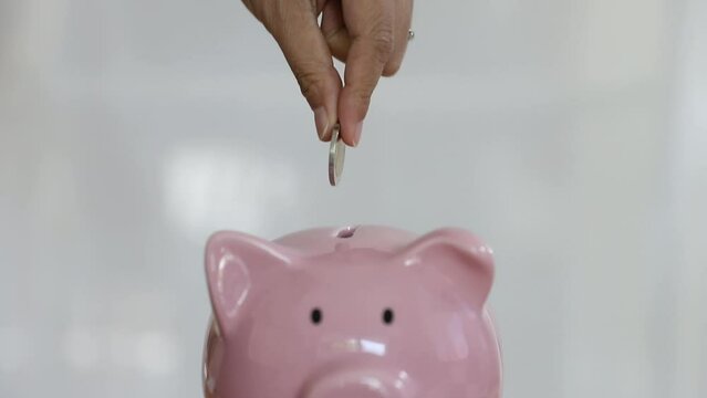 A hand put coin into piggy bank for saving money and business investment concept