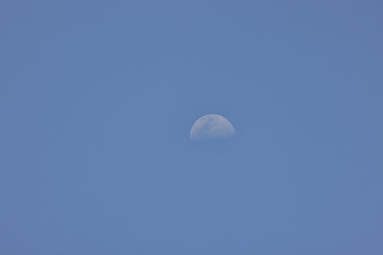 A Top Side Of A Bright Half Moon Far Away In The Clear Blue Sk