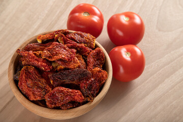 Fresh tomatoes and sun-dried tomatoes on wooden background
