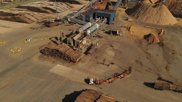 Aerial shot of industrial crane unloading wooden trunks of Truck for production line in paper mill factory