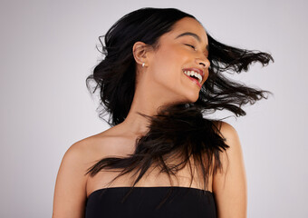 A good hair day is a good YOU day. Studio shot of a young woman shaking her hair while standing against a grey background.