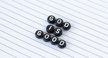 God is good, text written with black circle letters isolated on white lined paper. The Christian...