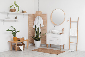 Interior of light bathroom with sink, mirror and wooden folding screen