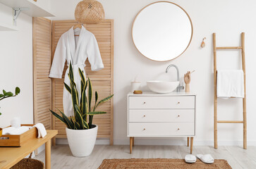 Interior of light bathroom with sink, mirror and wooden folding screen