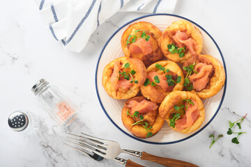 Yorkshire pudding. Traditional English Yorkshire pudding with salmon and radish microgreens side dish on white plate and light grey background table. Top view.