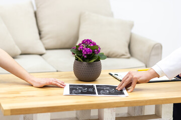Photo of ultrasound photo on the table and two hands.