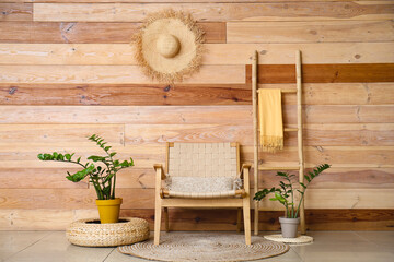 Stylish armchair, houseplants and ladder near wooden wall