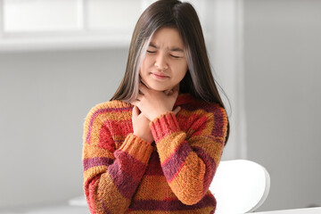 Ill Asian girl with sore throat at home