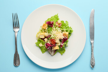 Plate with tasty vegan Caesar salad on blue background