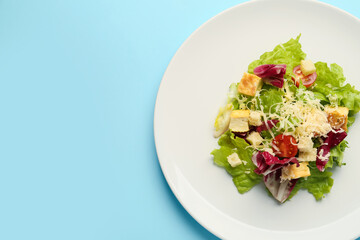Plate with tasty vegan Caesar salad on blue background