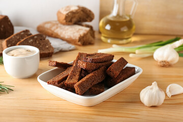 Bowl with tasty rye croutons on table