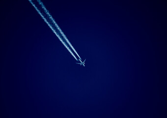 Airplane leaving a condensation trail in the blue sky.