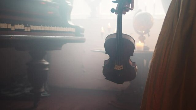 A Young Girl And Man Plays The Violin In A Beautiful Retro Room With Flowers And A Piano.
