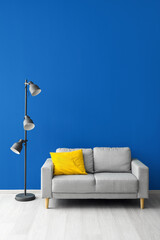Stylish sofa and lamp near blue wall