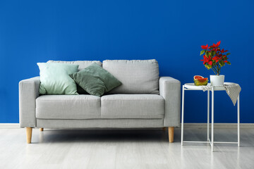 Stylish sofa and table near blue wall