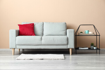 Stylish sofa and table near beige wall