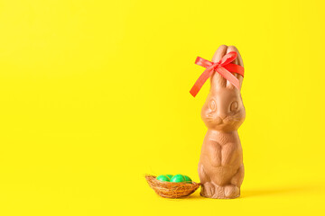Chocolate Easter bunny with ribbon and candies on yellow background