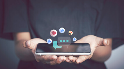 Live Chat on Communication social network Concept. Person hand using smartphone typing, playing social media chatting conversation in chat box icons pop up.