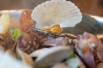 Close-up of a scallop with open mouth on top of steamed clams