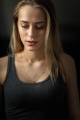 Naklejka premium Portrait of a young beautiful fair-haired girl close-up in a low key.